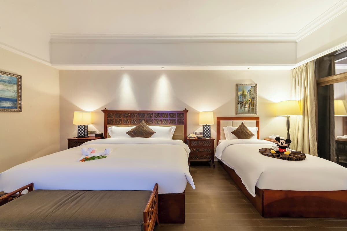 Una habitación de hotel con dos camas, mesitas de noche, lámparas y cuadros en las paredes.
