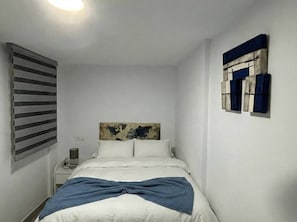 A bedroom with a bed, a nightstand, a lamp, and a wall-mounted artwork. - Ecija Confort by Casa Yaye (Écija)