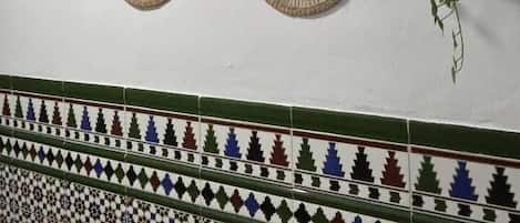 Pared adornada con tres tapices tejidos y un friso de azulejos estampados.