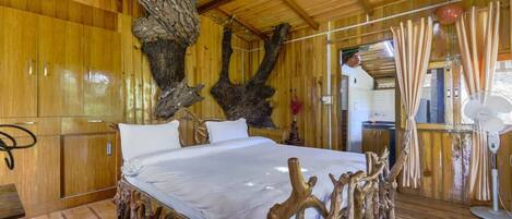 Una habitación de madera con una cama, paredes de madera y un gran tronco de árbol.