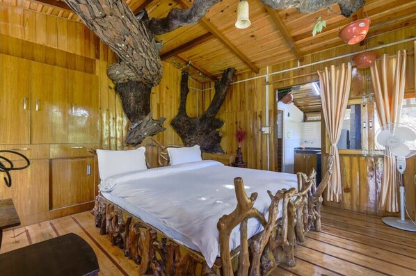 Una stanza in legno con un letto, pareti in legno e un grande tronco d'albero.
