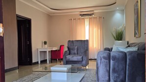 Ein modernes Wohnzimmer mit einem grauen Sofa, einem roten Sessel und einem Glastisch.