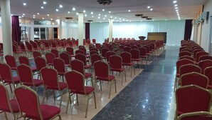 Ein großer Saal mit Reihen roter Stühle und einer Bühne.