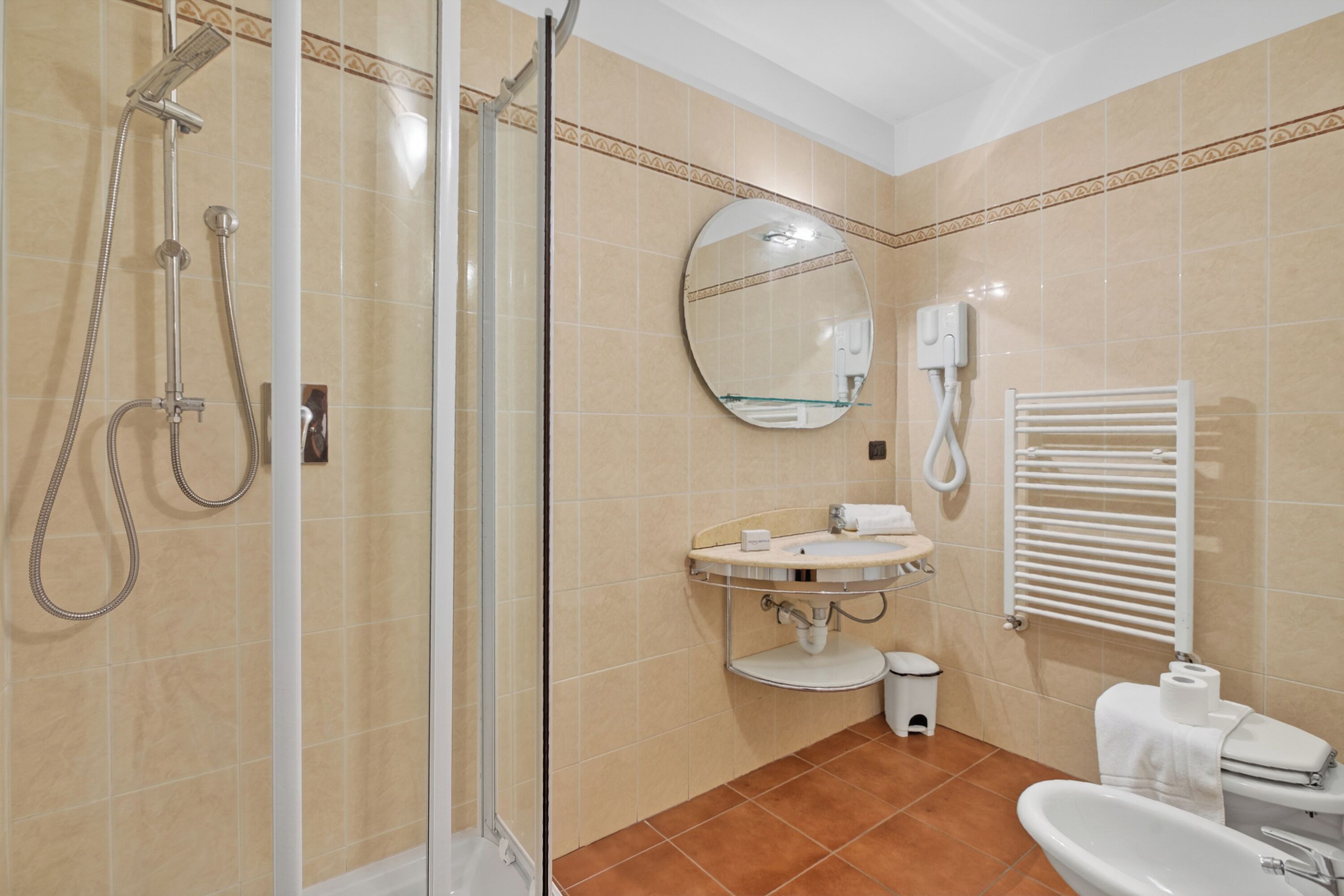 A bathroom with a shower, sink, toilet, and a mirror.