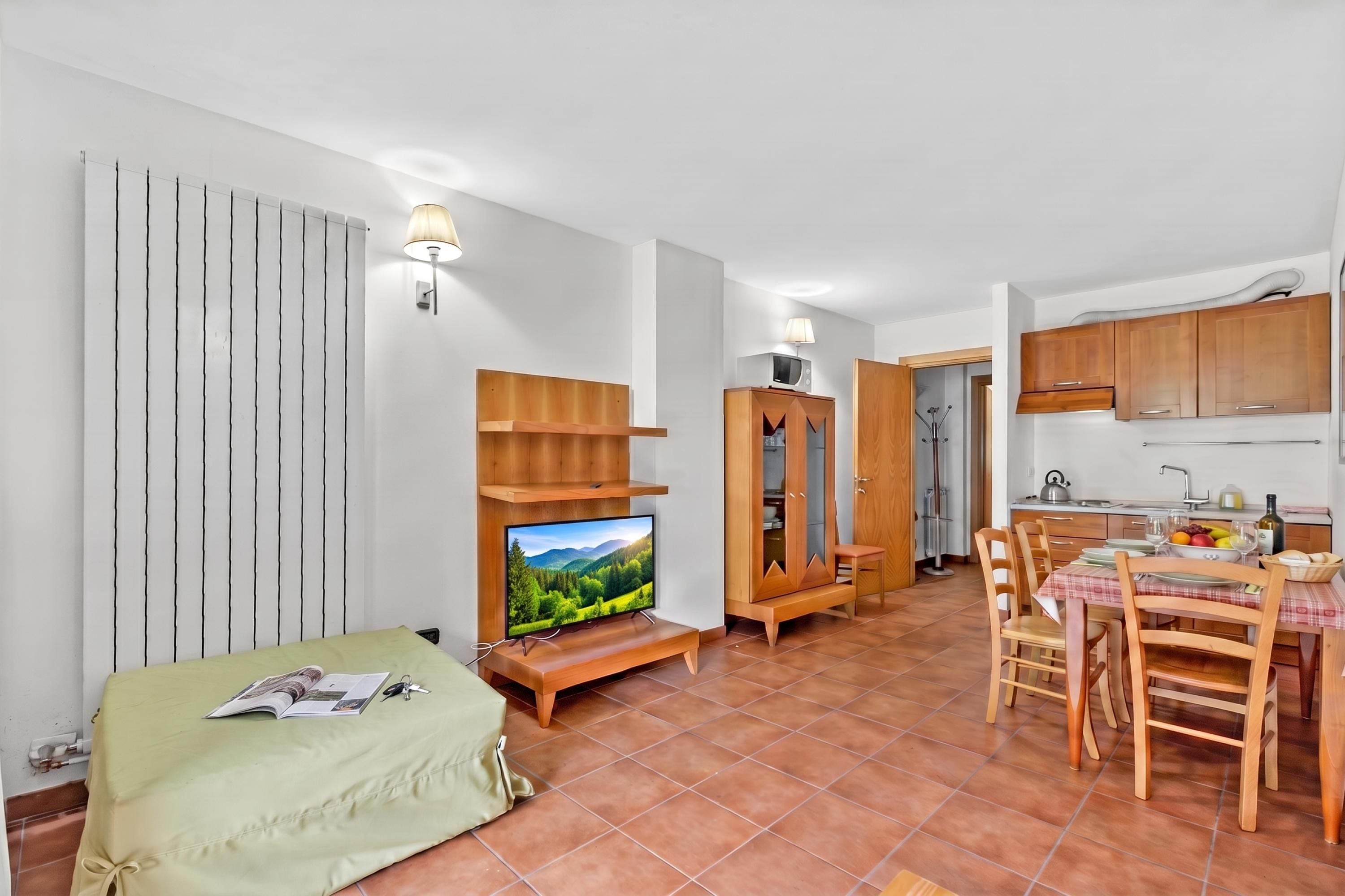 A compact living space with a television, a dining area, and a kitchenette.