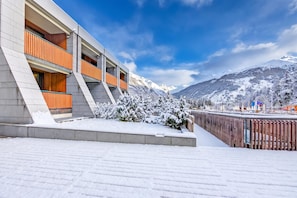 A modern building with a snow-covered landscape and mountains in the background. - Hercules's House Ski-in/ski-out (Bardonecchia)