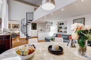 A modern living room with a marble table, a vase of flowers, a staircase, and a sofa. - TREVI FOUNTAIN COZY AND FABULOUS APARTMENT (Roma)
