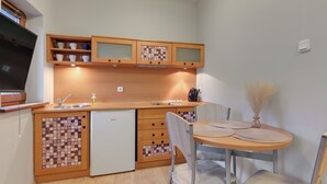 Cozinha compacta com armários de madeira, máquina de lavar louça embutida e área de jantar com mesa redonda e cadeiras.