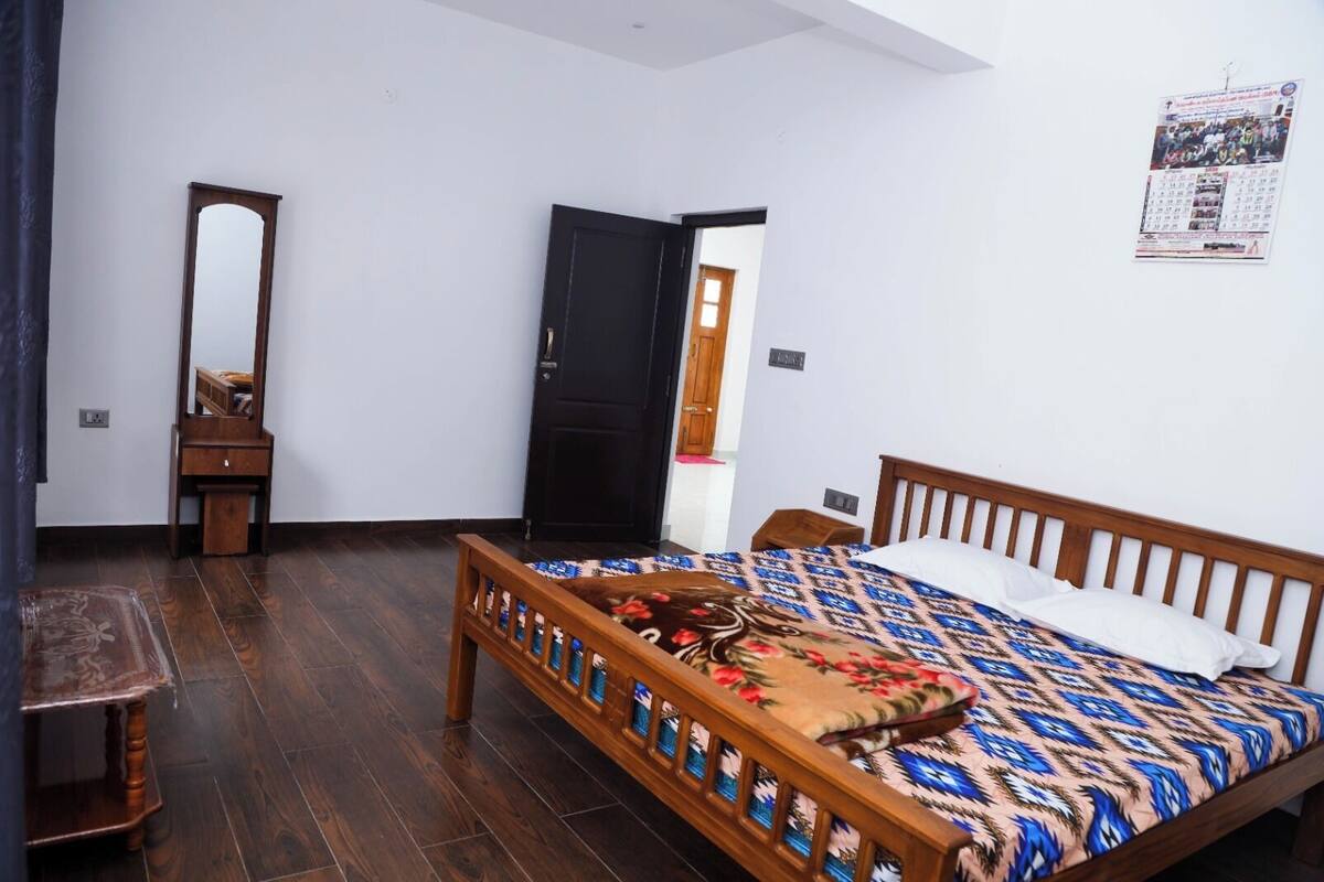 Een slaapkamer met een houten bed, een nachtkastje, een dressoir en een spiegel.