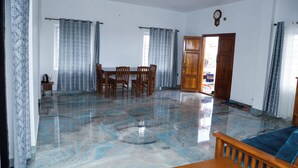 Amplia sala de estar con piso de mármol pulido, un comedor de madera y un sofá azul.