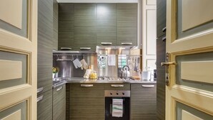 A compact kitchen with a built-in oven, stainless steel appliances, and a hanging pot rack. - PIAZZA DI SPAGNA FABULOUS AND COZY APARTMENT (Roma)