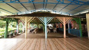 A covered outdoor seating area with wooden flooring and a metal roof structure. - Nivant Agro Experience (Vada)