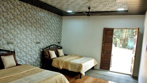 A room with two beds, a ceiling fan, and a door leading outside. - Nivant Agro Experience (Vada)