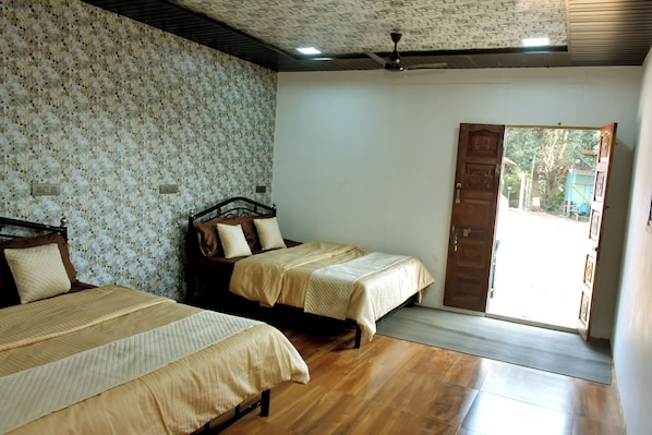 A room with two beds, a ceiling fan, and a door leading outside.
