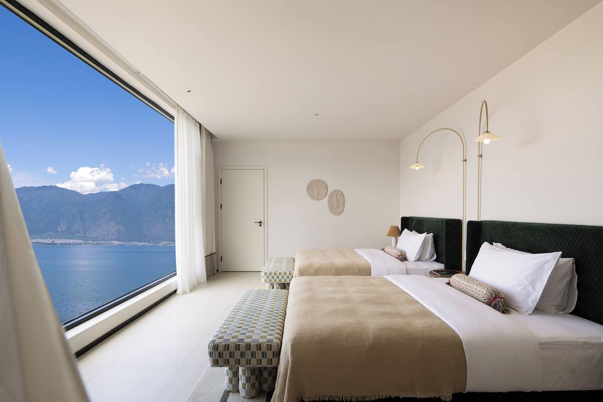 Ein Schlafzimmer mit zwei Betten, Meerblick und einer Tür zu einem anderen Raum.