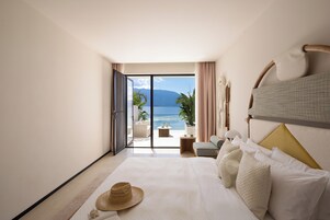 Habitación de hotel con cama, un sombrero y vista al mar.