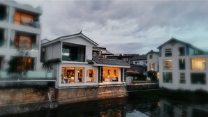 Un edificio a la orilla del río con comedor y balcón con vistas al agua.
