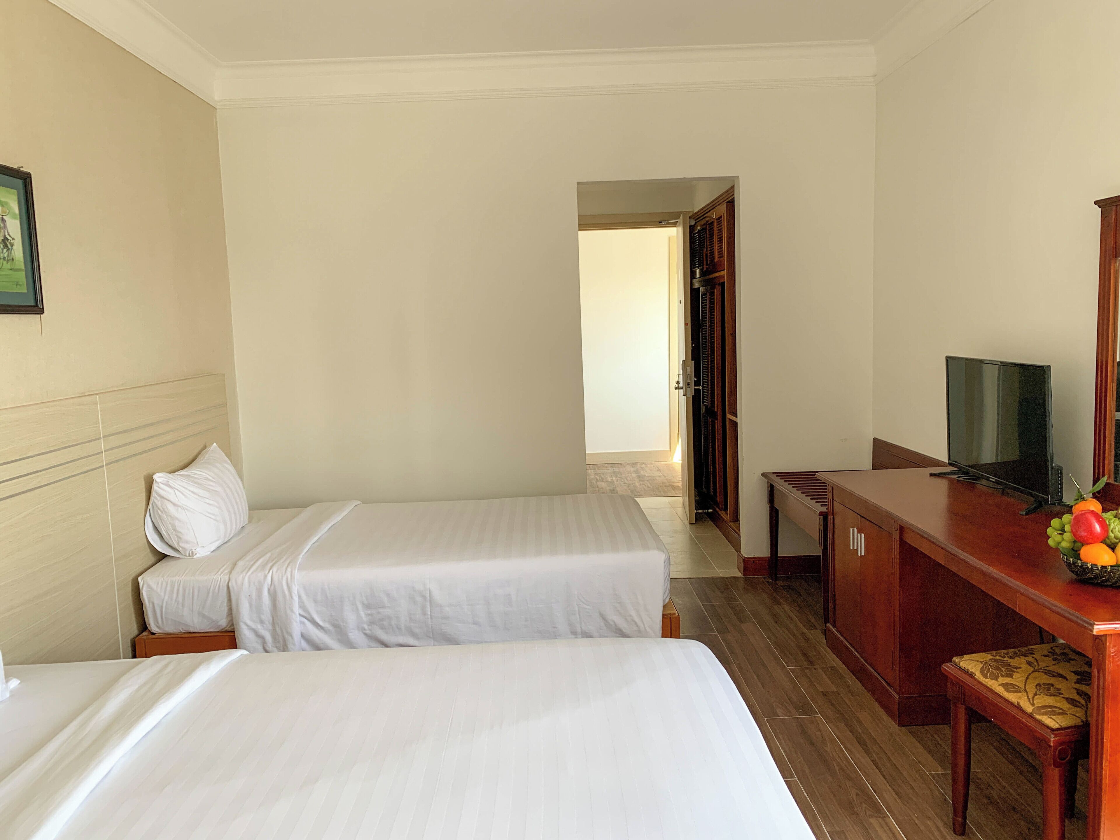 Una habitación de hotel con dos camas, televisión, escritorio y silla.