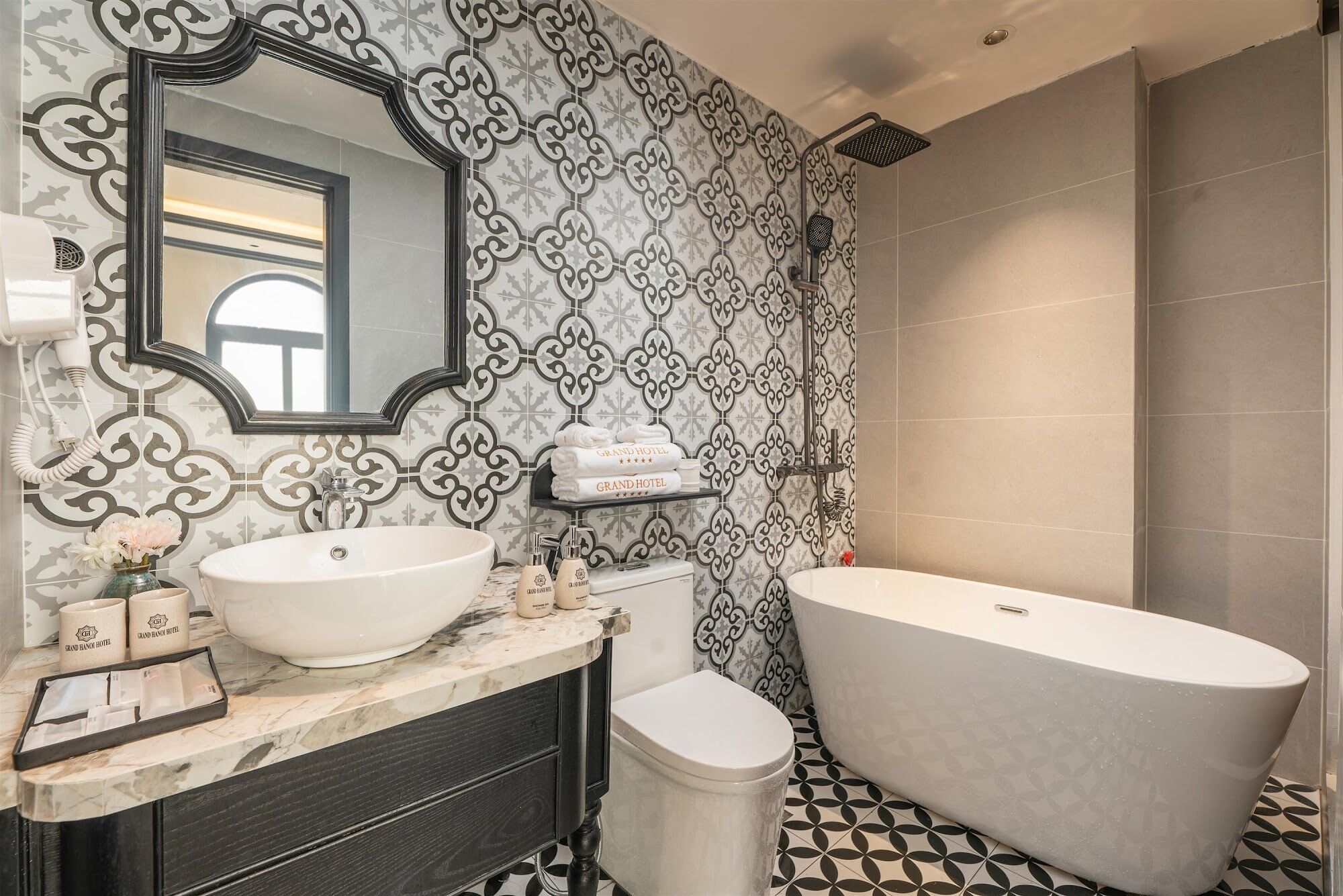A bathroom with a freestanding bathtub, a large mirror, and a vanity with a sink and towel dispensers.