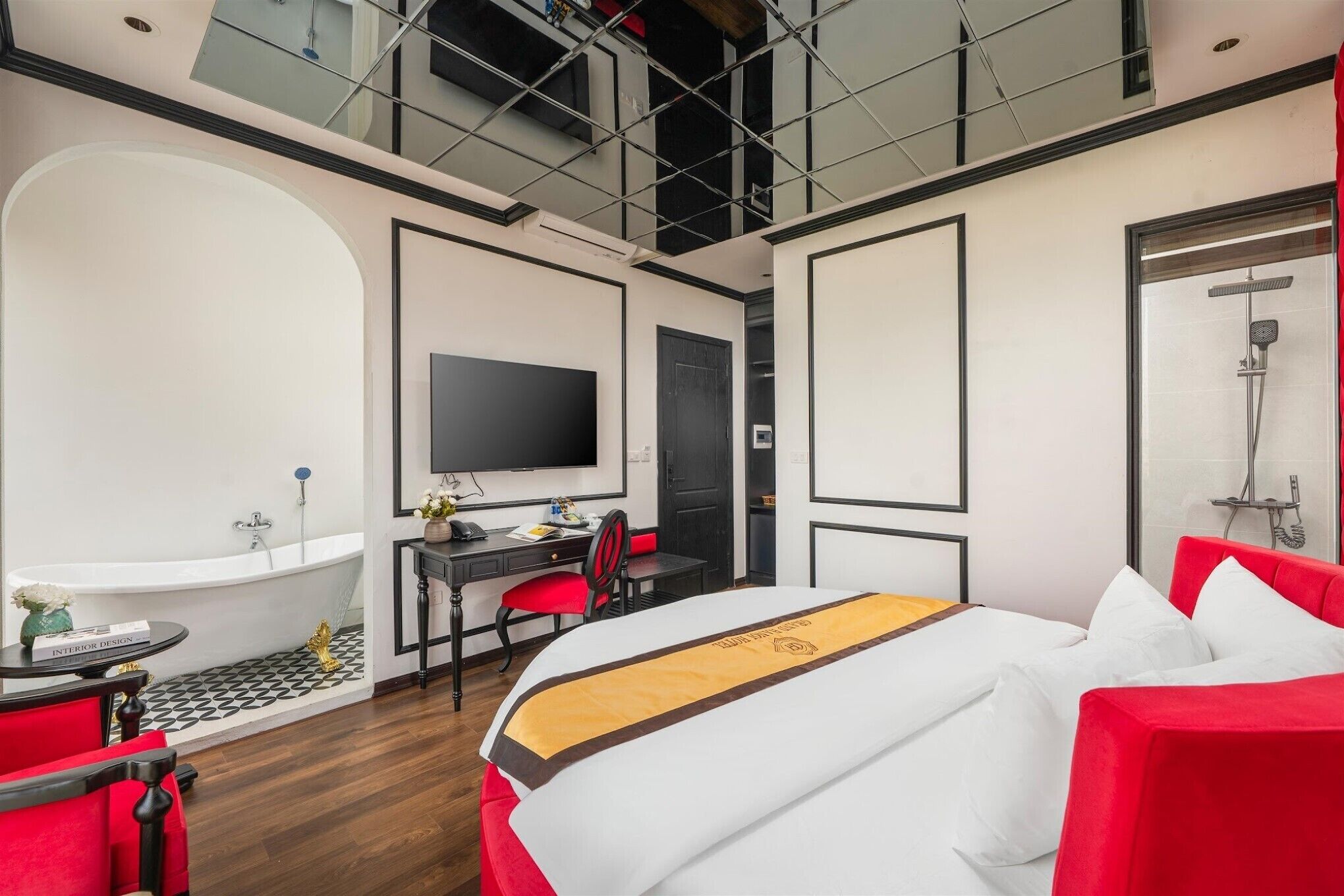 Habitación de hotel moderna con una cama grande, un escritorio, una silla, un televisor, una bañera y una ducha.