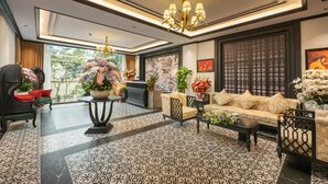 Un salon spacieux doté d’un parquet à motifs, d’un lustre et d’un canapé agrémenté de coussins à motifs.