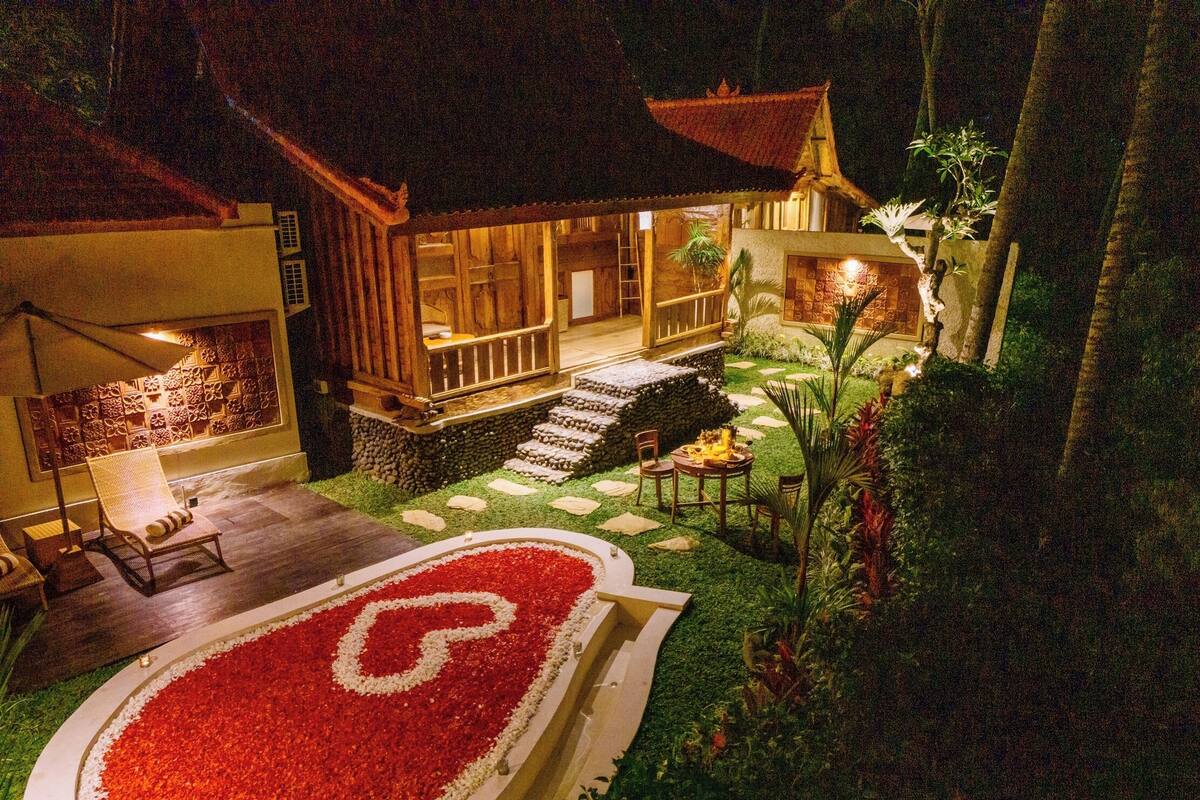 A traditional wooden building with a thatched roof, surrounded by a well-maintained garden with a stone pathway leading to a wooden deck.