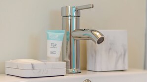 Un lavabo de salle de bain avec un robinet chromé, un porte-savon et un tube de lotion.