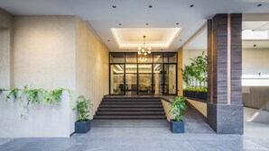 A modern hotel entrance with a staircase leading to a reception area, featuring a geometric ceiling design and potted plants. - Effotel By Sayaji Sangli (Miraj)