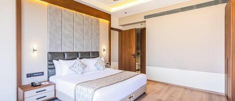 Una habitación de hotel moderna con una cama grande, una mesita de noche con teléfono y un ventilador de techo.