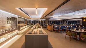 A modern restaurant with a central serving counter, multiple seating areas, and a decorative wall with framed pictures. - Effotel By Sayaji Sangli (Miraj)