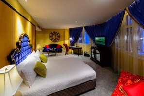 A hotel room with a large bed, a desk with a computer, a television, and a red chair. - Aurum Royal (Singapore)