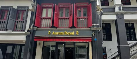 A building with a sign reading "Aurum Royal" and a staircase leading to an upper level.
