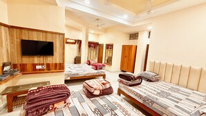 A hotel room with two beds, a flat-screen TV mounted on the wall, a ceiling fan, and a wooden wardrobe. - Hotel P & L near Mahakaleshwar Temple  (Ujjain)