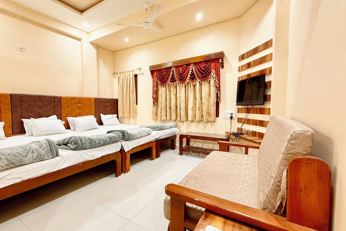 Una habitación de hotel con una cama grande, un sofá, un televisor y un ventilador de techo.
