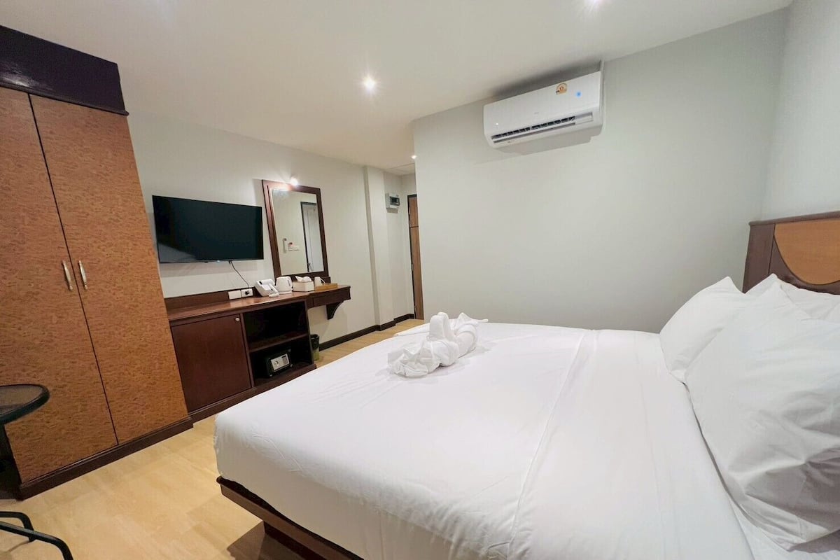 Habitación de hotel con cama, escritorio con espejo, armario y aire acondicionado.