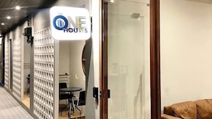 Pasillo de hotel con diseño moderno, que incluye un separador de vidrio, un sofá y un letrero con el nombre del hotel.