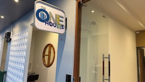 Un cartel para 'The One Houses' con un diseño moderno, puerta de entrada de vidrio y cámara de seguridad.