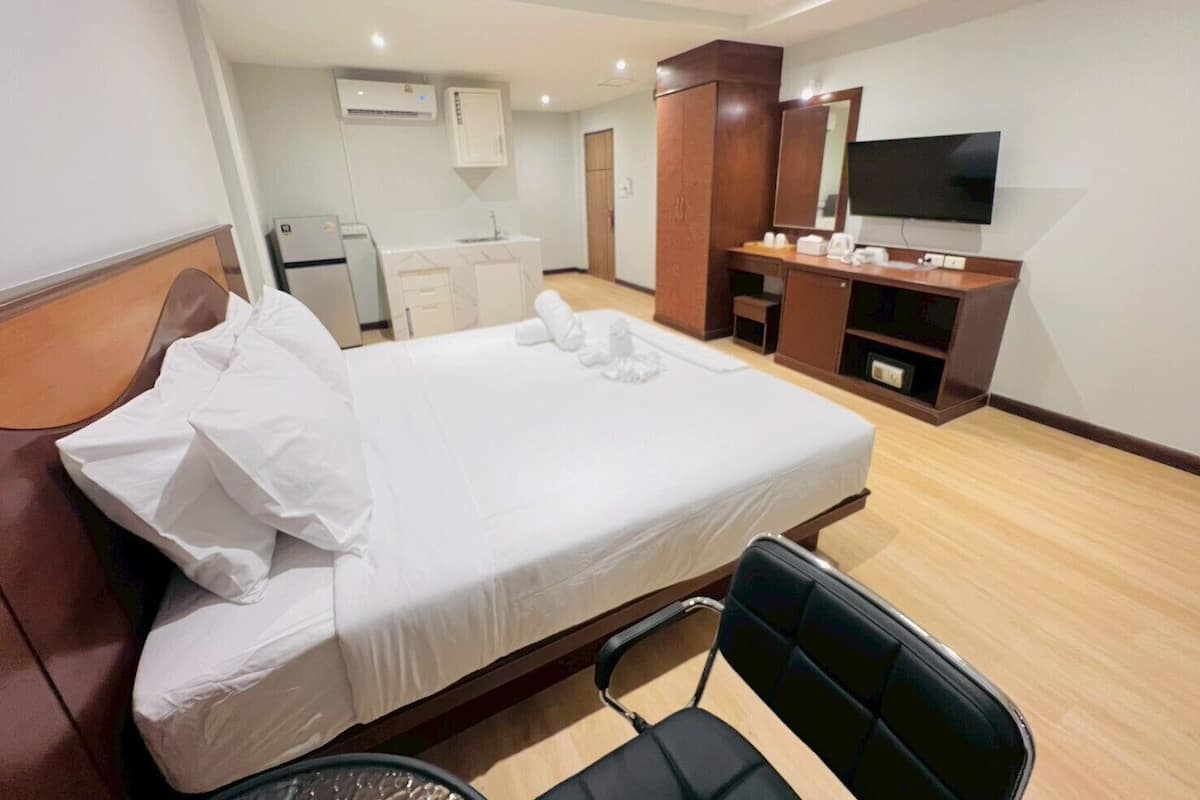 Una habitación de hotel con una cama, un escritorio, una silla, un televisor y un armario.