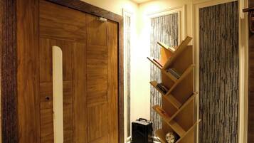 Una habitación con un armario de madera, una estantería y un papel tapiz estampado.