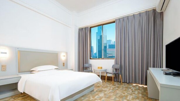 Een hotelkamer met een bed, een bureau, een stoel, een tafeltje en een televisie.