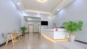 Een moderne receptie met een receptiebalie, een zithoek en potplanten.