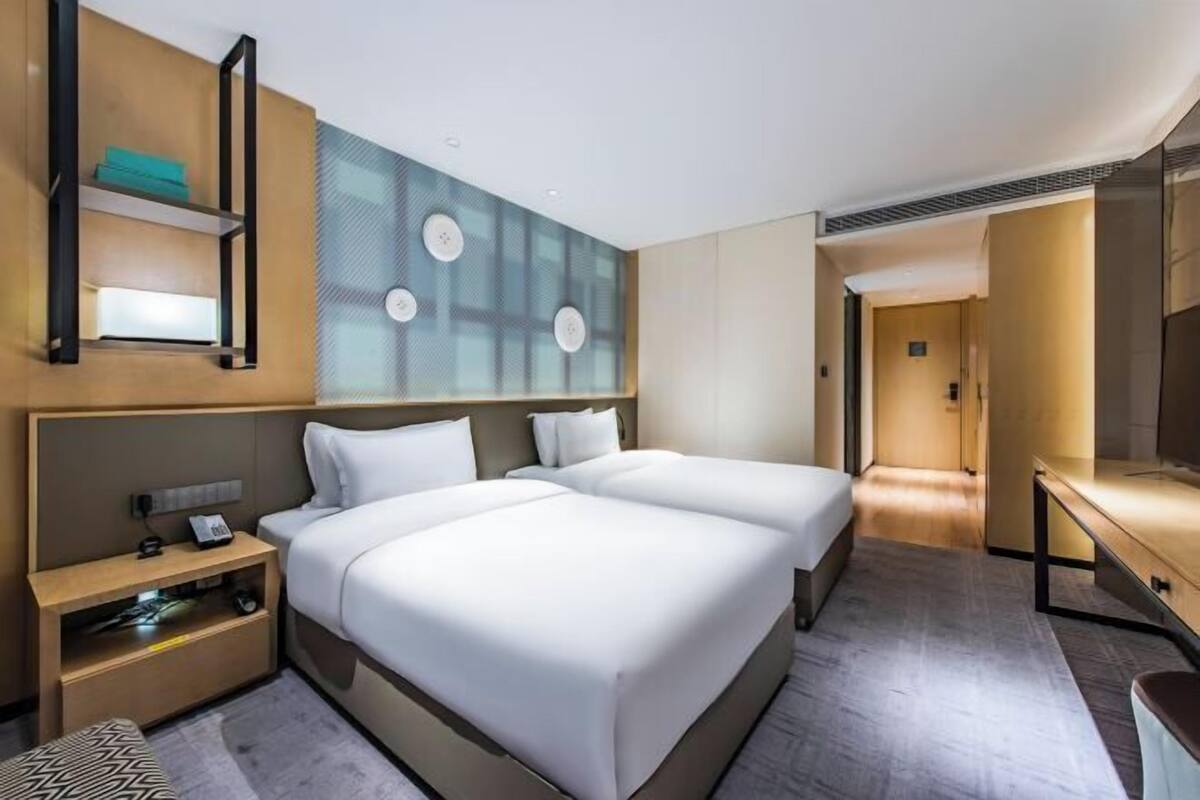 A hotel room with two beds, a desk, a TV, and a minibar.