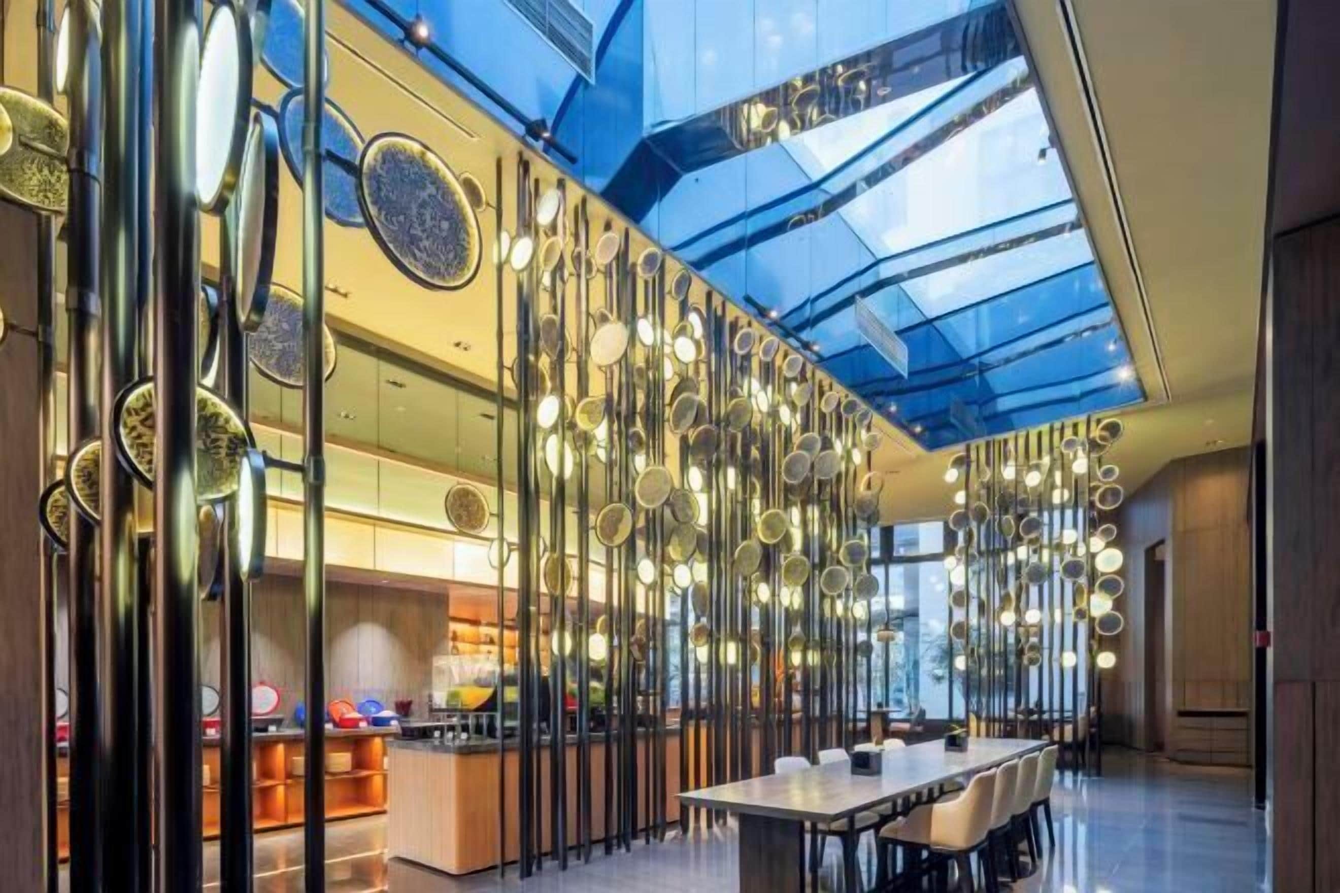 Un intérieur moderne avec un plafond haut, des surfaces réfléchissantes et un espace de salle à manger central.