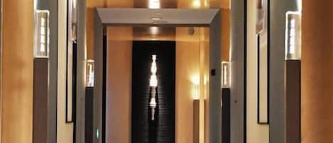 A hallway with a central light fixture and mirrored walls.