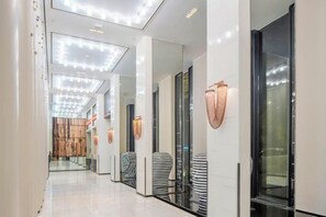 A modern hotel corridor with reflective surfaces, glass doors, and contemporary lighting fixtures. - Intercity Hangzhou Qingchun Road Hotel (Hangzhou)