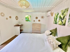 Quarto com cama, janela, pia e detalhes decorativos na parede.