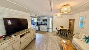 Ein gemütlicher Wohnbereich mit Fernseher, Küchenzeile, Essbereich und einer Couch.