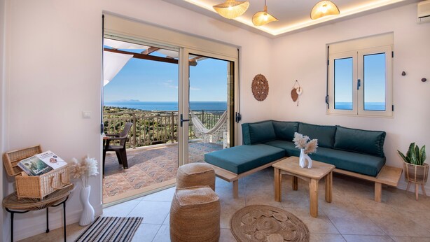 Una sala moderna con sofá, una mesita de centro y una mesa de comedor. Hay un balcón con vistas al mar.