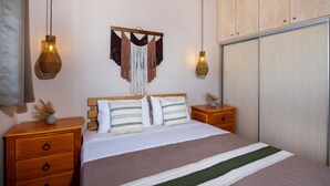 Un dormitorio ordenado con cama, mesitas de noche, una lámpara colgante y un armario.