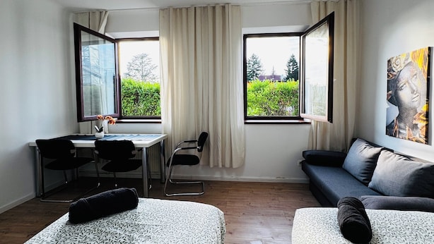 Ein modernes Hotelzimmer mit zwei Betten, einem Schreibtisch, einem Stuhl und einer Couch.